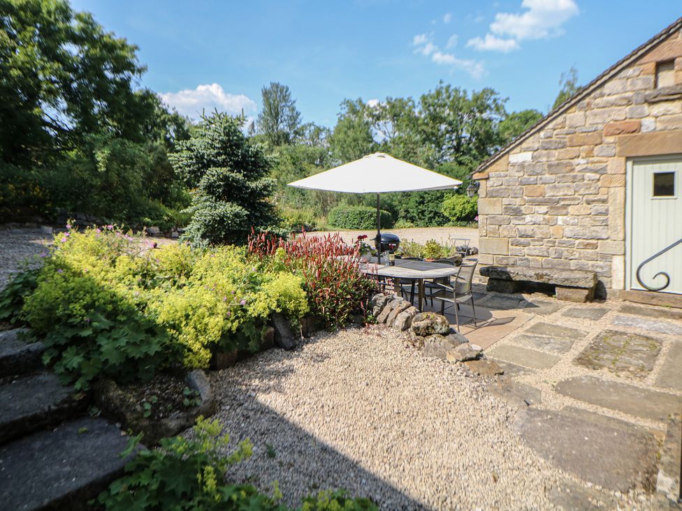 A garden area with a table and umbrella at Green Farm Stables in Hognaston near Carsington Water