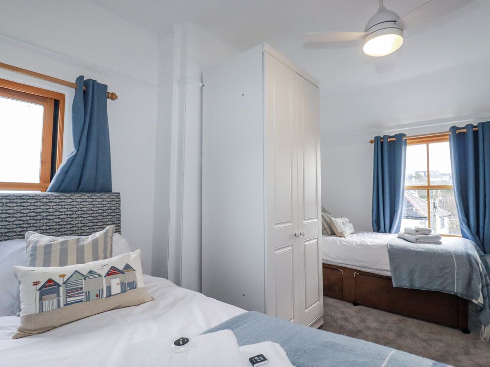 A bedroom with two beds and a wardrobe at Tresawle in Crantock