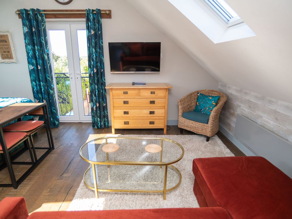 A living room with a television and a dining table at Garden View Apartment in Kingsbridge