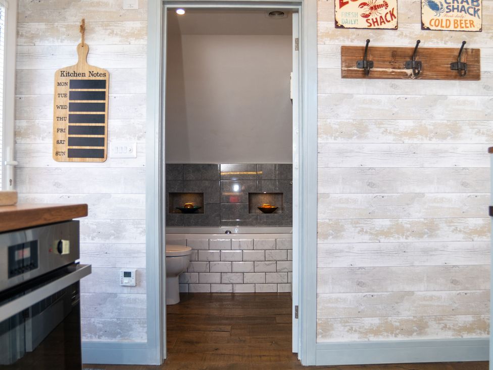 A kitchen with a view of a bathroom doorway at Garden View Apartment in Kingsbridge