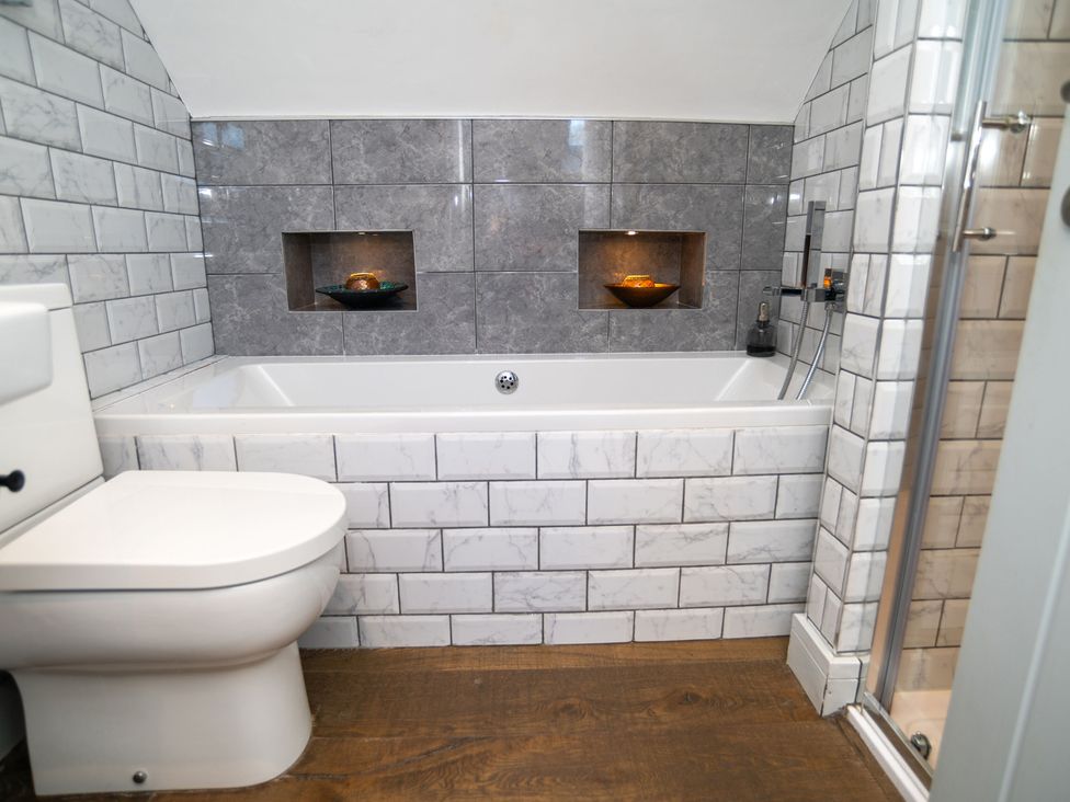 A bathroom with a bathtub, toilet, and shower at Garden View Apartment in Kingsbridge