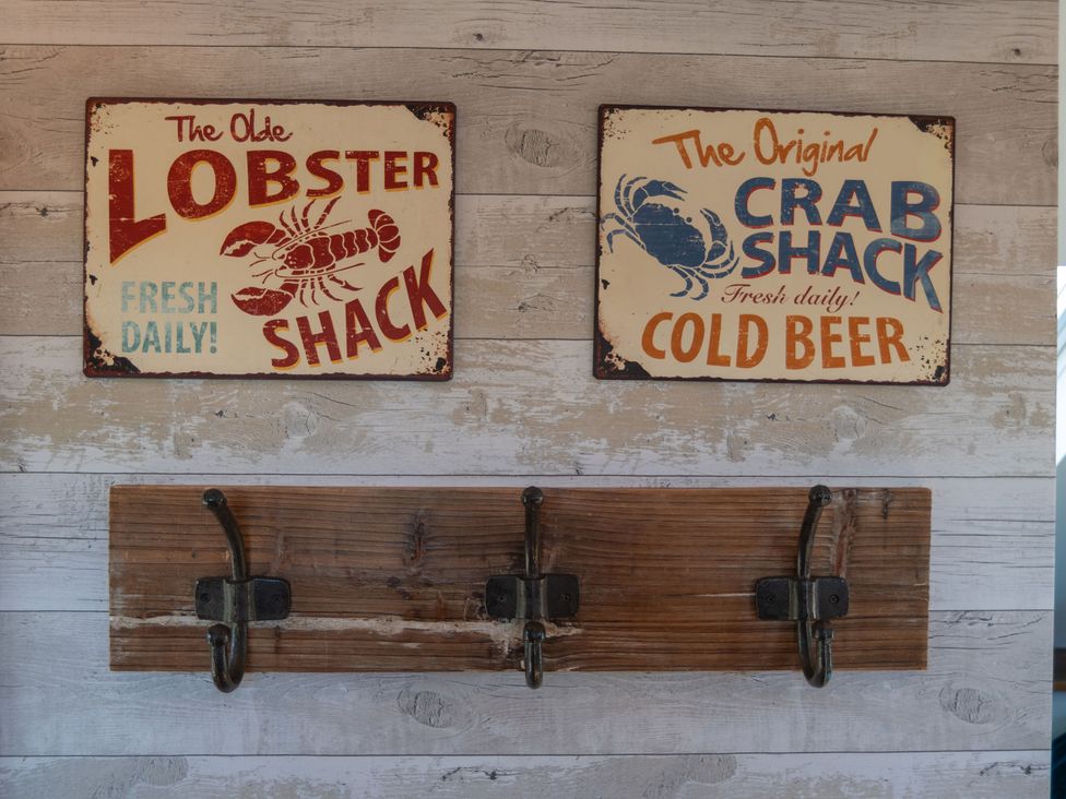 A wooden panel with lobster and crab signs and hooks at Garden View Apartment in Kingsbridge