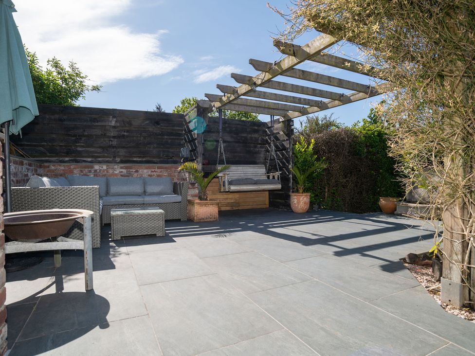 A patio area with outdoor seating and a swing seat at Garden View Apartment in Kingsbridge