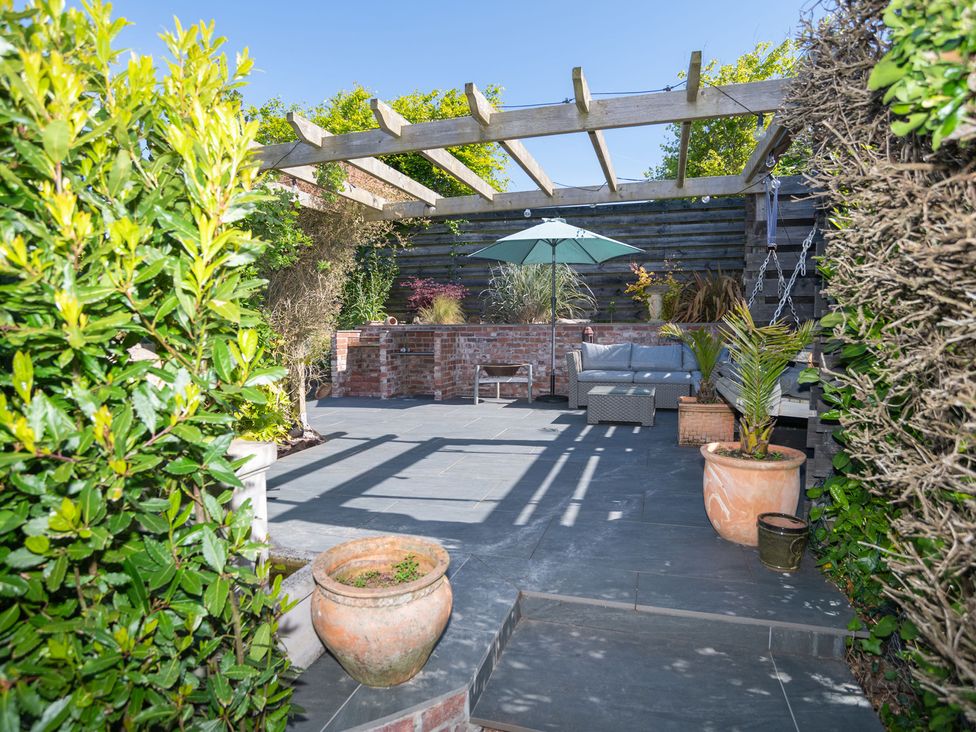 A garden with a patio and a couch under a pergola at Garden View Apartment in Kingsbridge