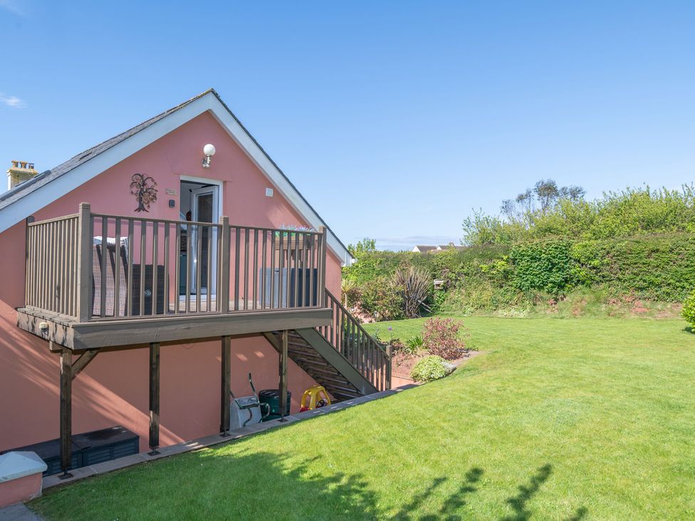 A garden with a house featuring a balcony at Garden View Apartment in Kingsbridge