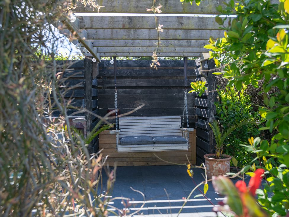 A swing seat with cushions in a garden area at Garden View Apartment Kingsbridge