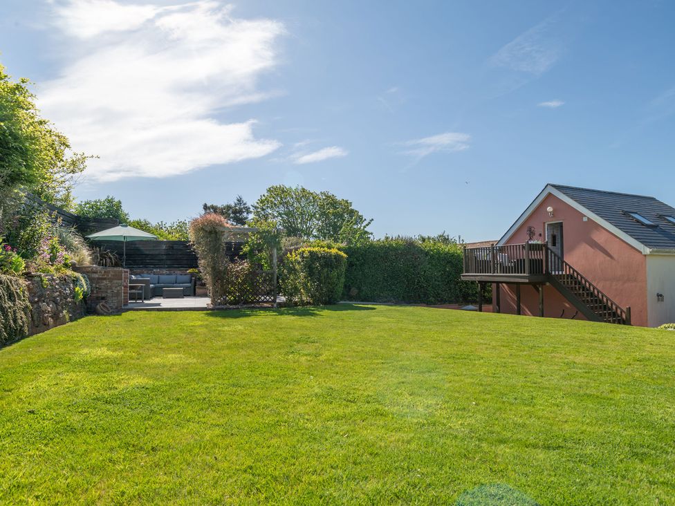 A garden with grass and a deck at Garden View Apartment in Kingsbridge