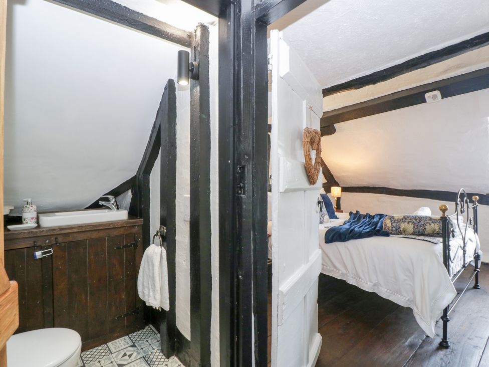 A bathroom with a wash basin and a bed in a room at Avonmede in Tewkesbury