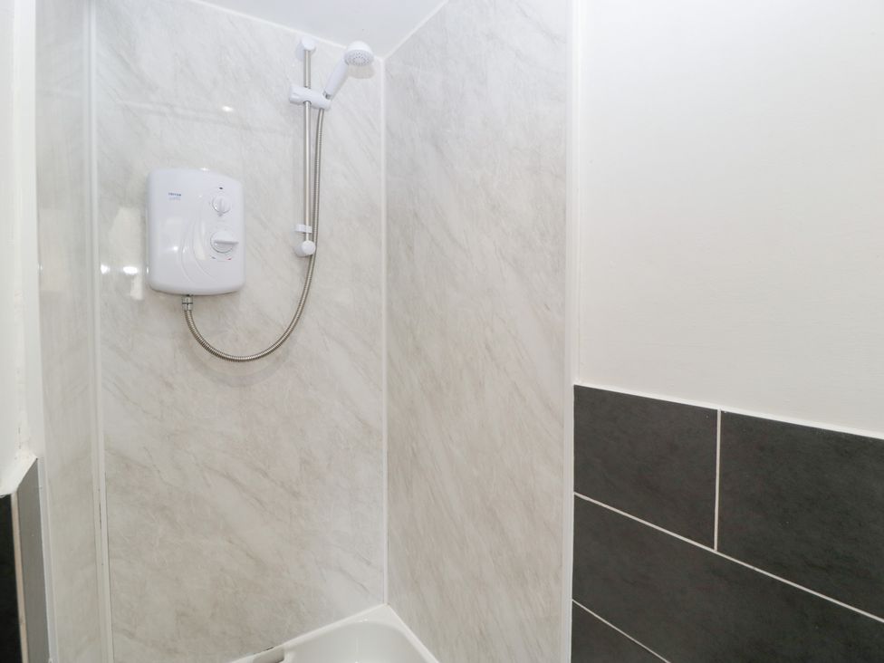 A shower with white walls and a black tiled accent at Avonmede Tewkesbury