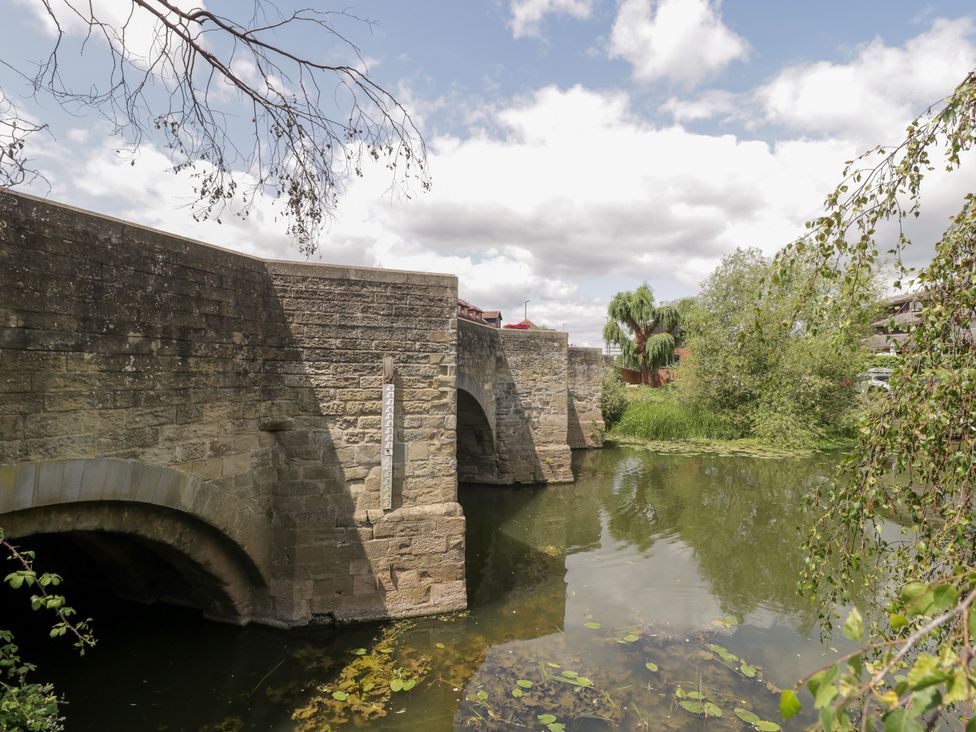 A bridge over water with trees and clouds at Avonmede in Tewkesbury