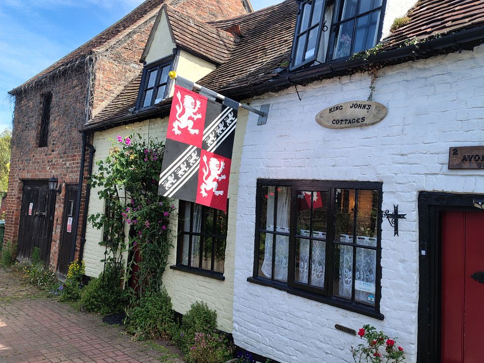 A view of King John's Cottages with flags and flowers in Tewkesbury