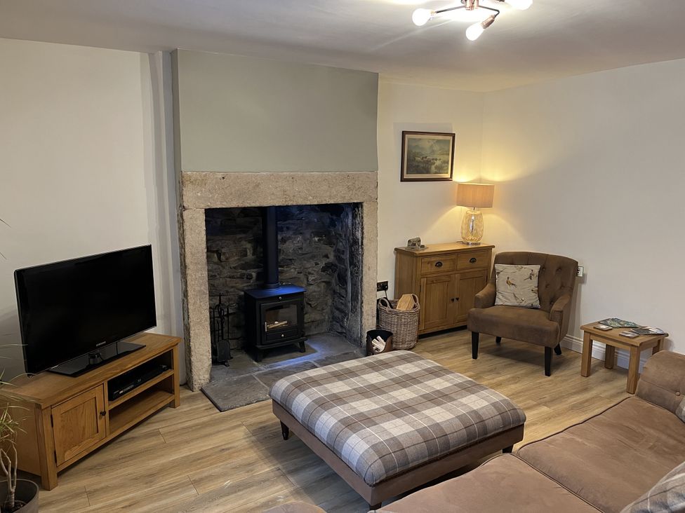 A living room with a wood stove and furniture at Bracken Cottage in Stanhope
