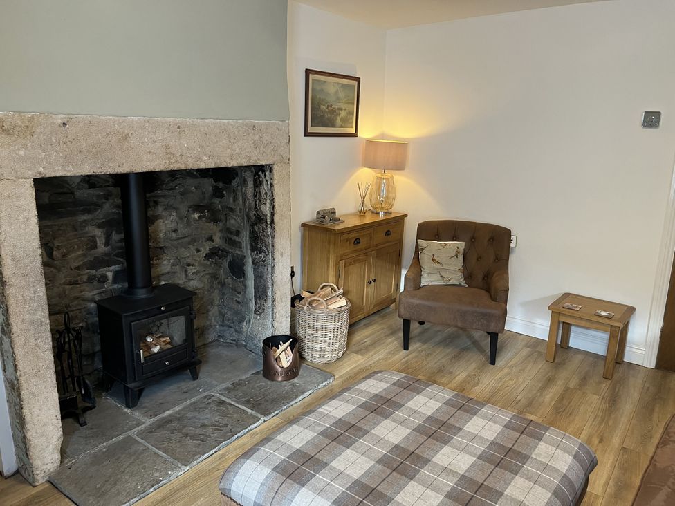 A living room with a fireplace and a chair at Bracken Cottage in Stanhope