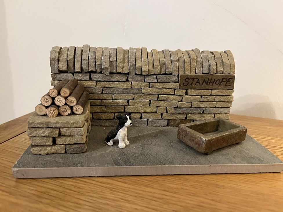 A decorative scene with a stone wall and a dog figurine at Bracken Cottage Stanhope
