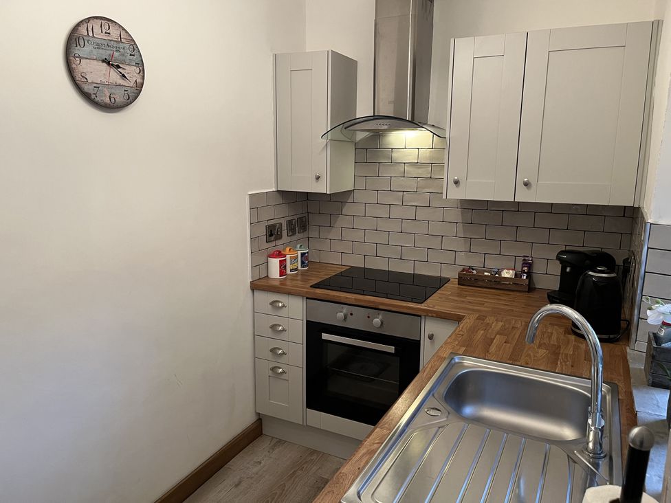 A kitchen with cabinets, countertop, oven and sink at Bracken Cottage in Stanhope