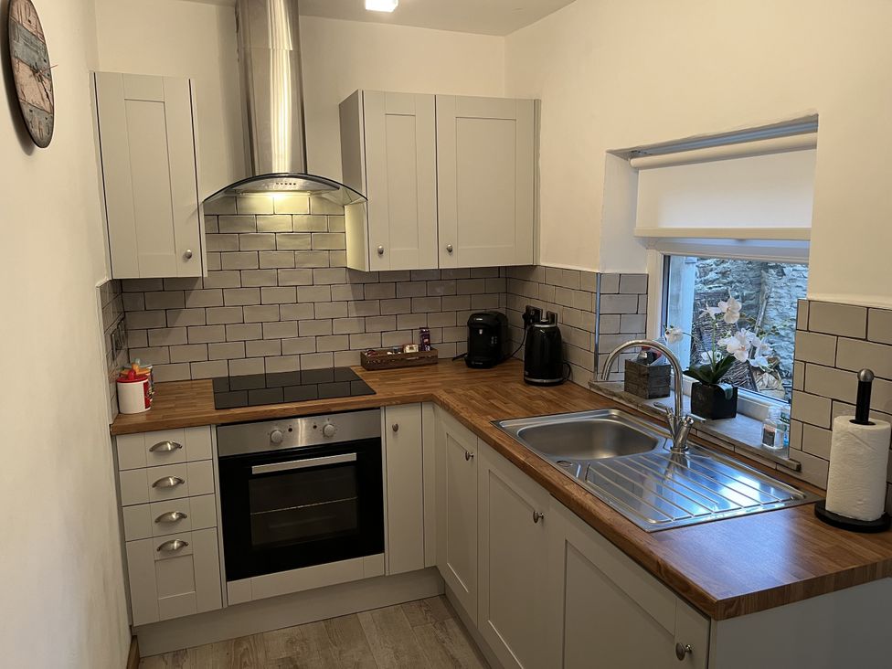 A kitchen with cabinets, a stove, and a sink at Bracken Cottage in Stanhope