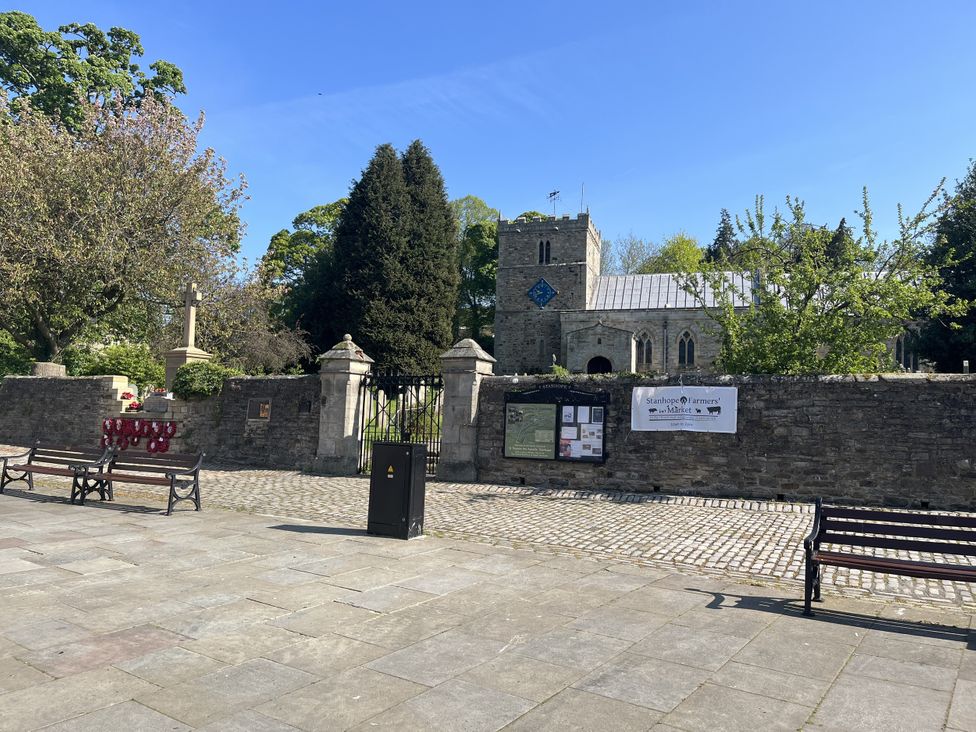 An outdoor view of a church with benches and trees at Bracken Cottage in Stanhope
