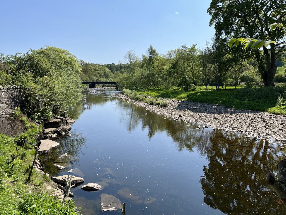 A river with trees and a bridge at Bracken Cottage in Stanhope