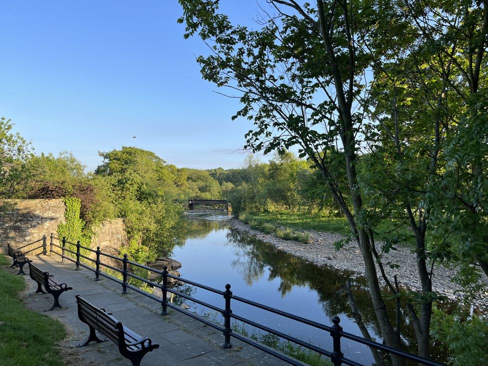 A river with benches and trees at Bracken Cottage in Stanhope
