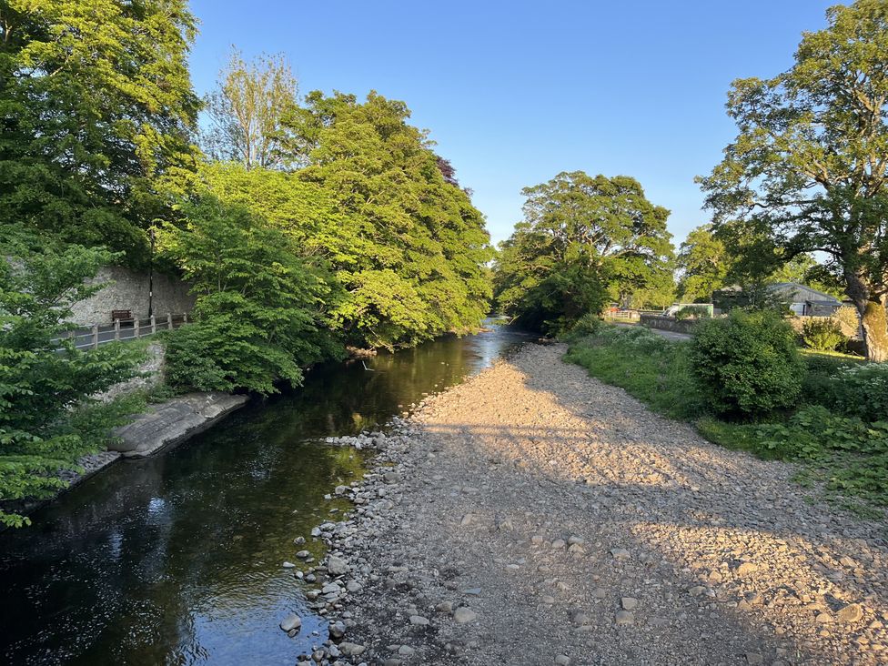A river bordered by trees and rocks at Bracken Cottage in Stanhope