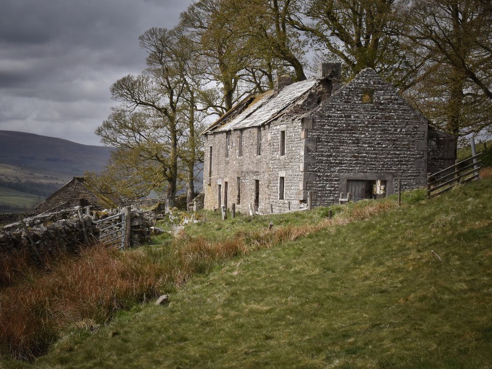 A stone building with trees and grass at Bracken Cottage in Stanhope