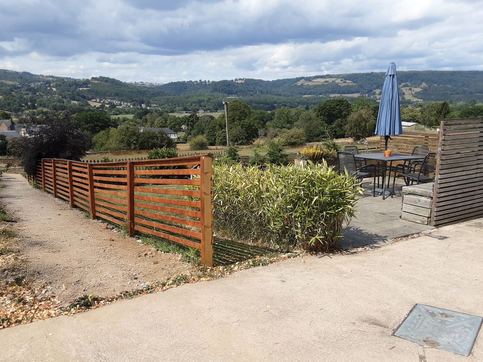 A garden with a table and chairs under an umbrella at Grove Farm Barn in Darley Dale
