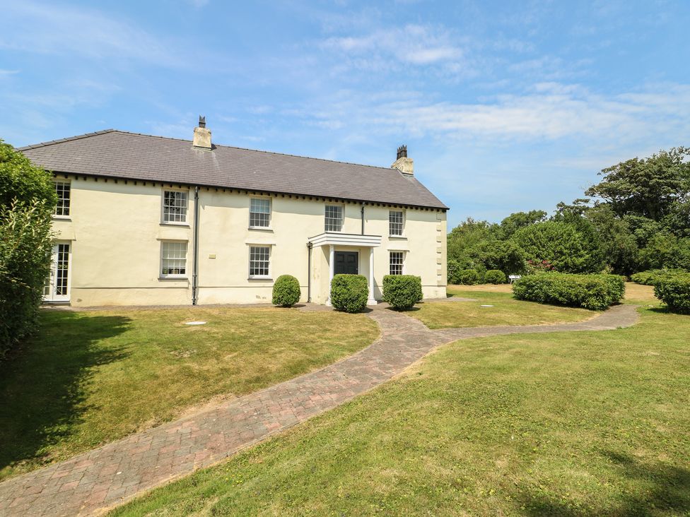 A house with a garden pathway and bushes at Clynnog House in Dwyran near Newborough