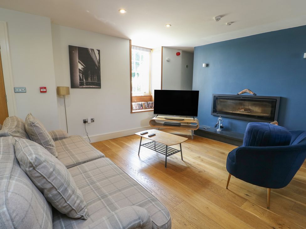 A living room with a sofa, coffee table, and television at Clynnog House in Dwyran near Newborough
