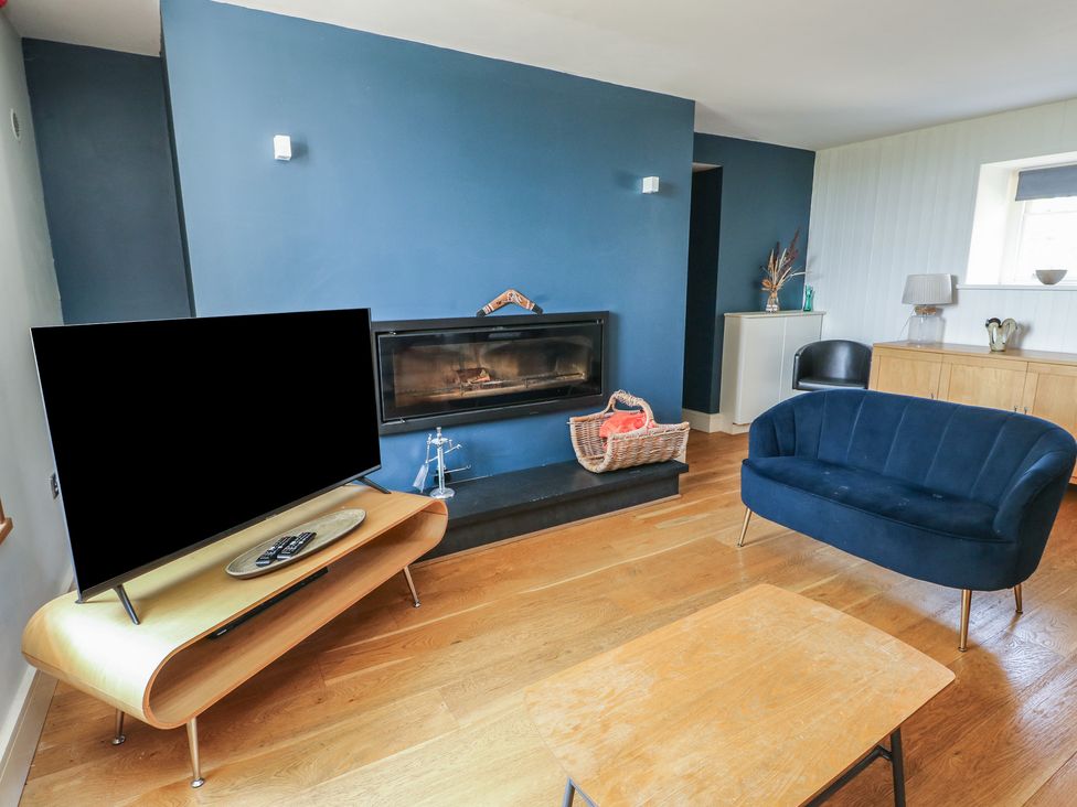 A living room featuring a television and a fireplace at Clynnog House Dwyran near Newborough