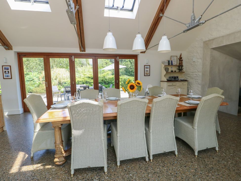 A dining room with a large table and sliding doors at Clynnog House in Dwyran near Newborough