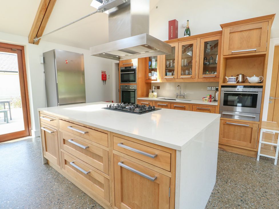 A kitchen with wooden cabinetry and appliances at Clynnog House in Dwyran near Newborough
