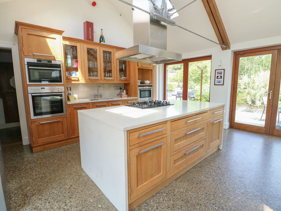 A kitchen with wooden cabinets and a central island at Clynnog House Dwyran near Newborough