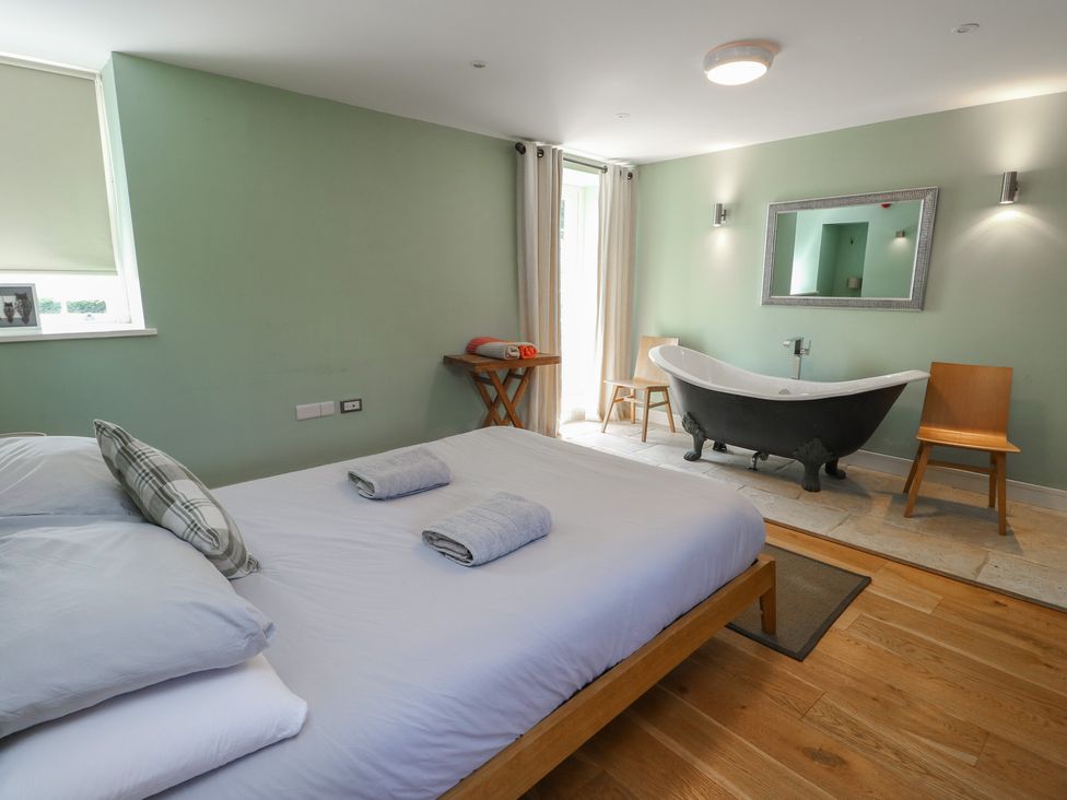 A bedroom with a bed and bathtub at Clynnog House in Dwyran near Newborough