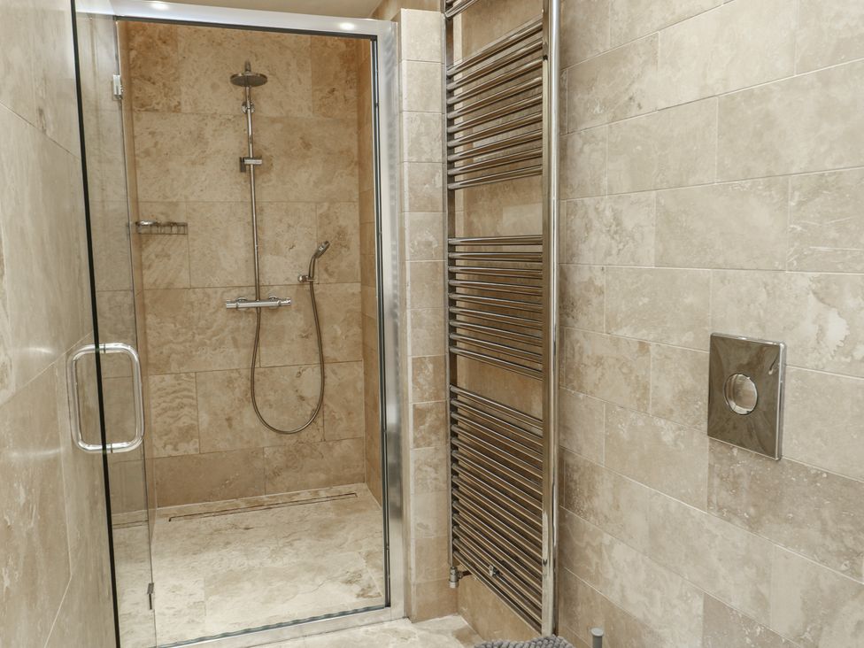 A bathroom with a shower and towel radiator at Clynnog House Dwyran near Newborough