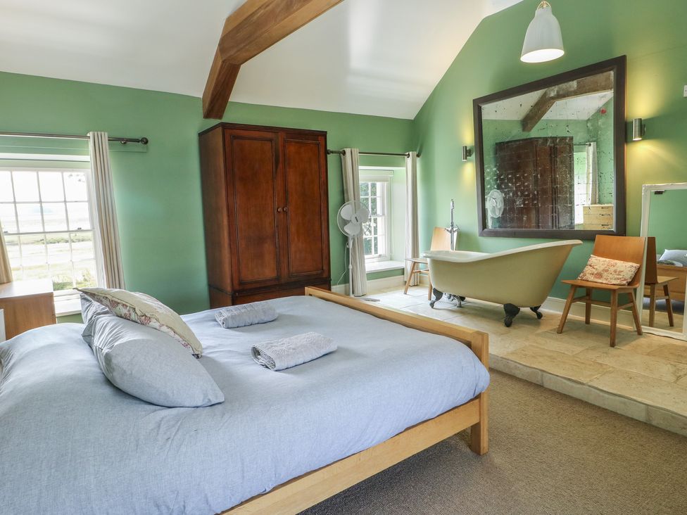 A bedroom with a bed and bathtub at Clynnog House Dwyran near Newborough