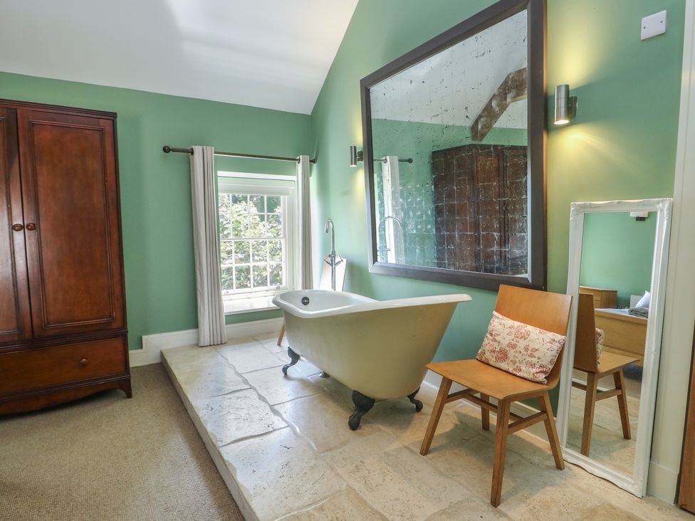 A bathroom with a bathtub and a mirror at Clynnog House in Dwyran near Newborough