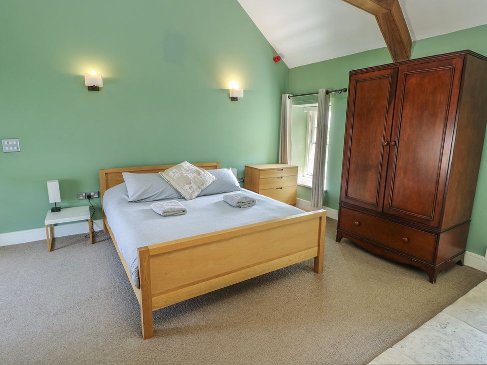 A bedroom with a bed and wardrobe at Clynnog House in Dwyran near Newborough