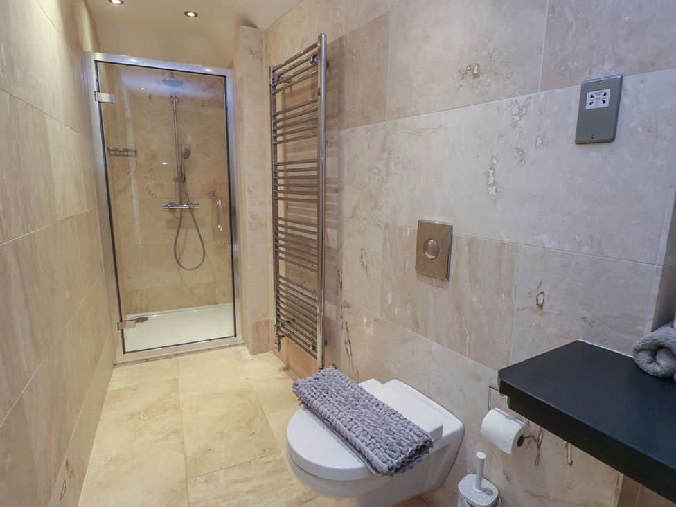 A bathroom with a shower enclosure and a toilet at Clynnog House in Dwyran near Newborough
