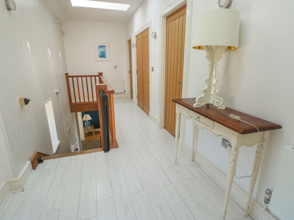 A hallway with a staircase and a console table at Clynnog House in Dwyran near Newborough