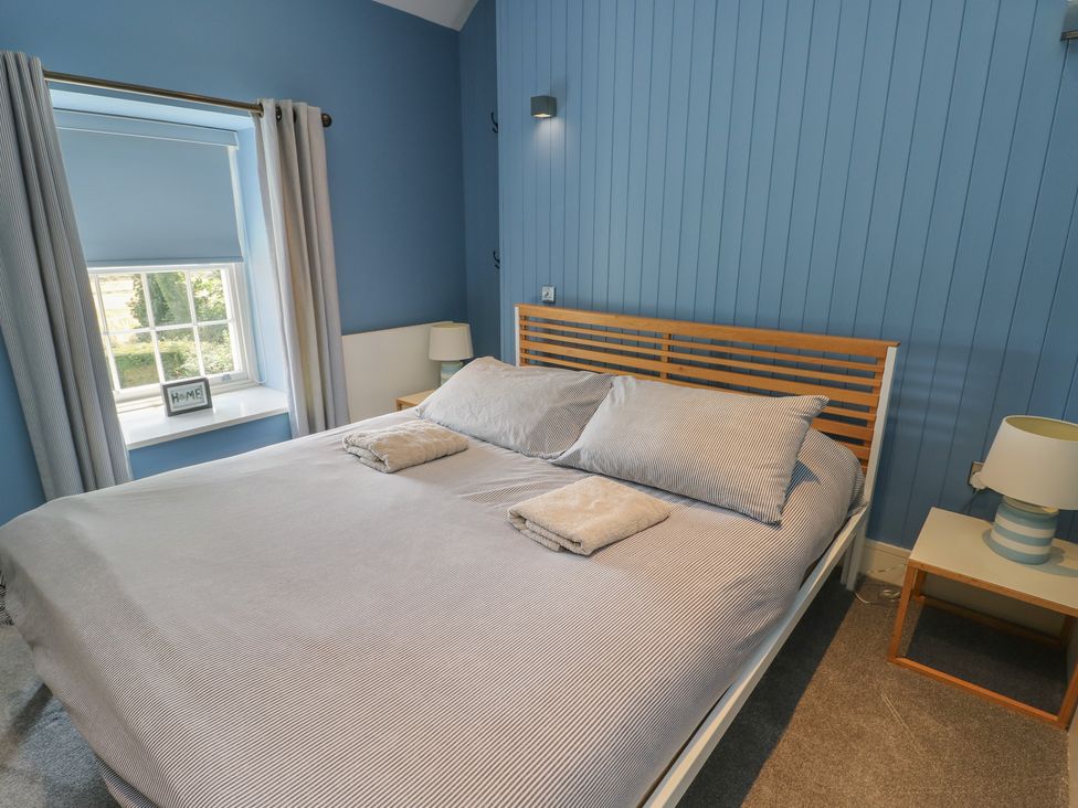 A bedroom with a bed and window at Clynnog House in Dwyran near Newborough