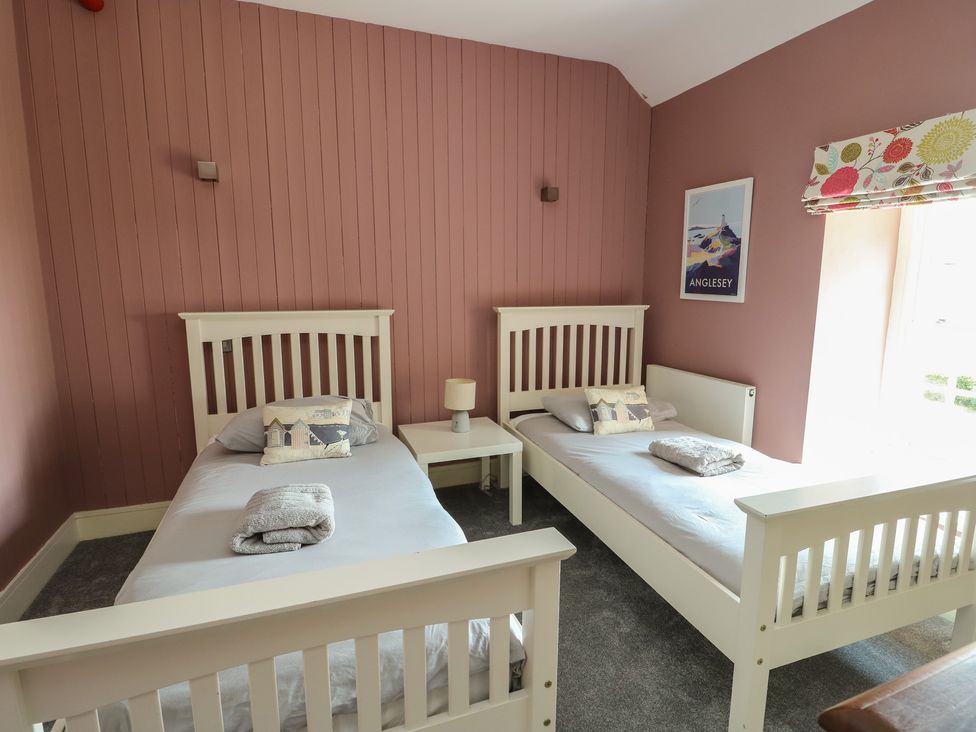 A bedroom with two single beds and a window at Clynnog House Dwyran near Newborough