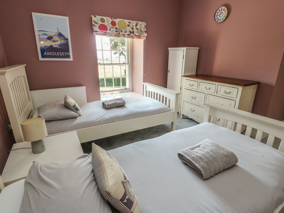 A bedroom with two beds and a chest of drawers at Clynnog House in Dwyran near Newborough