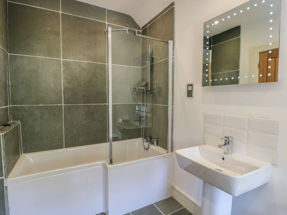 A bathroom with a bathtub and sink at Clynnog House in Dwyran near Newborough