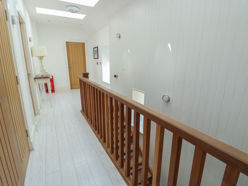 A hallway with a staircase and table at Clynnog House Dwyran near Newborough