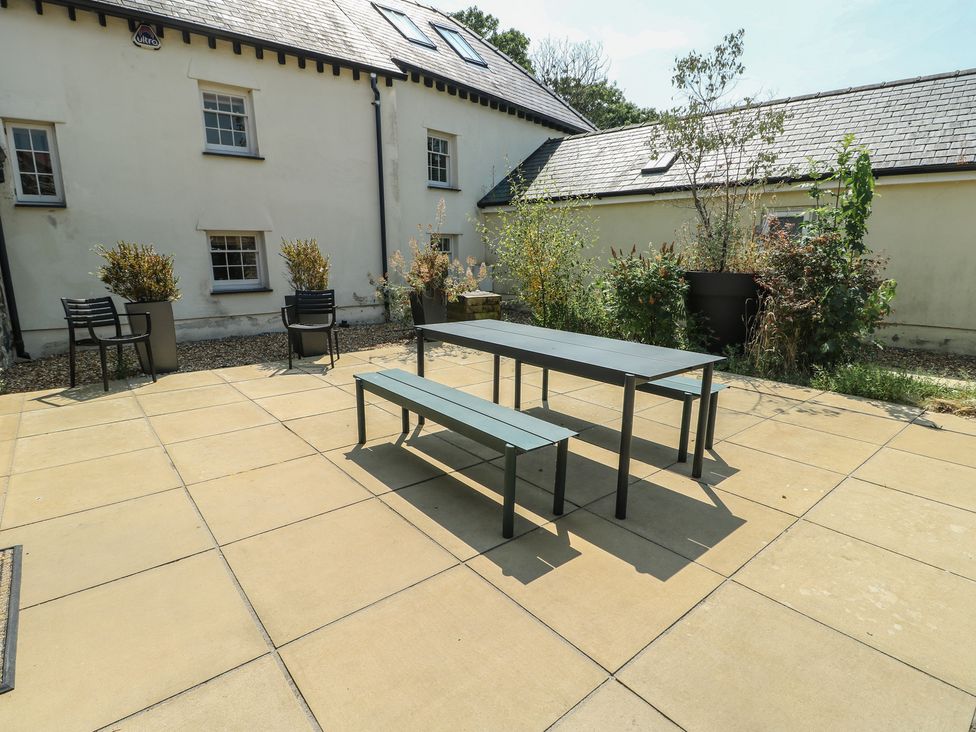 An outdoor area with a table and benches at Clynnog House in Dwyran near Newborough