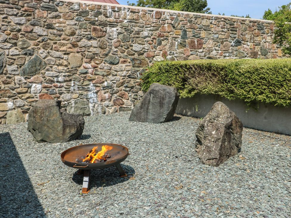An outdoor space with a fire pit and stones at Clynnog House in Dwyran near Newborough