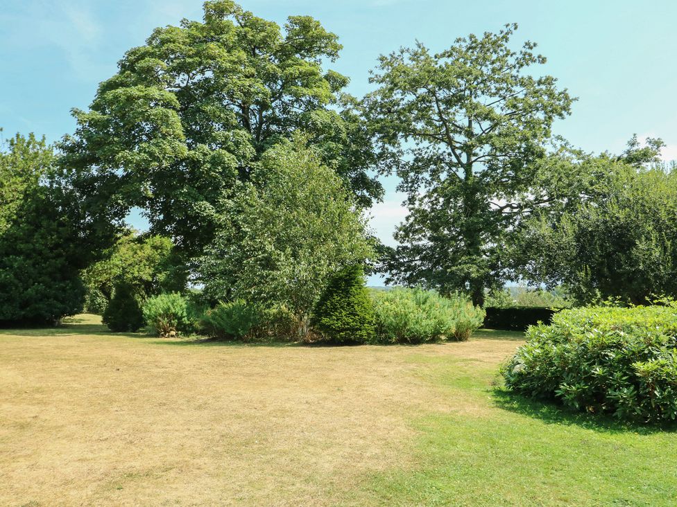 A garden with trees and bushes at Clynnog House in Dwyran near Newborough