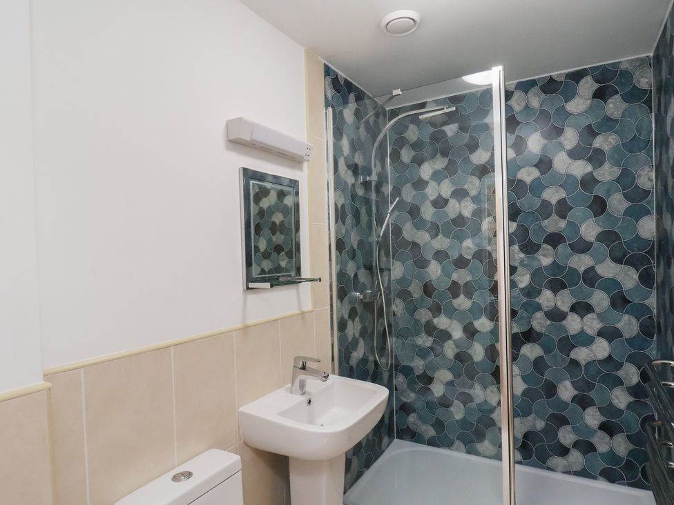 A bathroom with a shower, toilet, and sink at Sail Away, 17 Union Mill in Whitby
