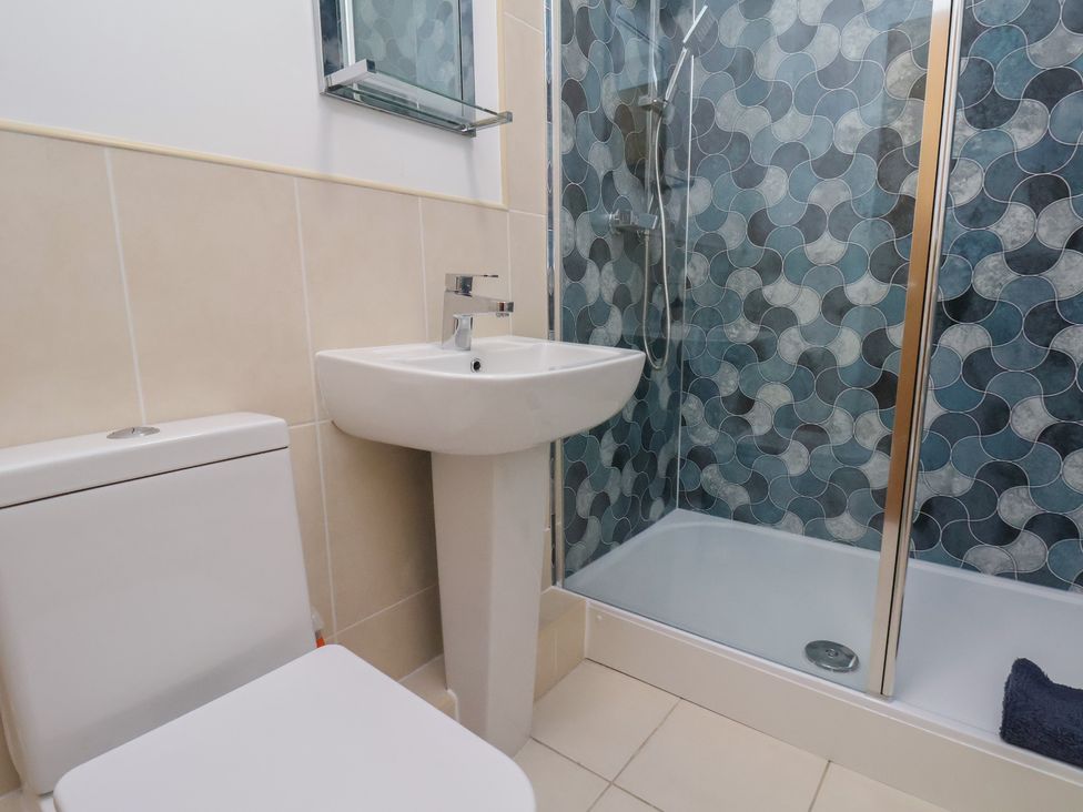 A bathroom with a toilet, wash basin, and shower at Sail Away, 17 Union Mill, Whitby
