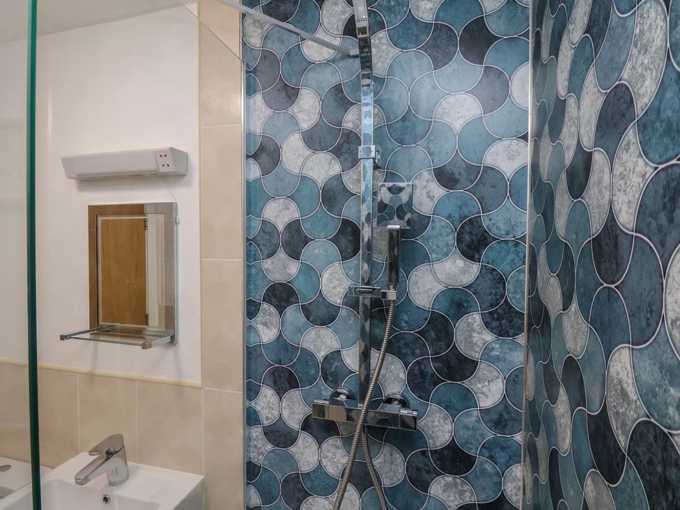 A bathroom with a shower, mirror, and sink at Sail Away, 17 Union Mill, Whitby